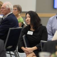 Guests sitting at tables, listening to speaker